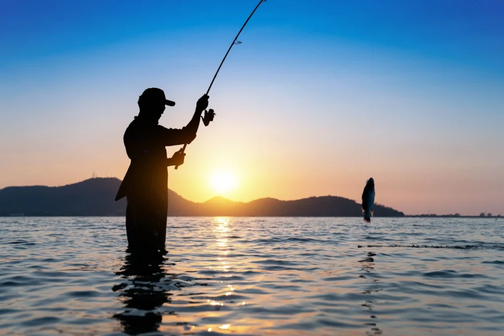 A man catching a Fish in the lake while the sunset marks his silhouette.