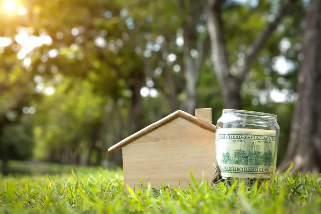 A small wood house with money next to it.